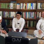 Ustadz Ahmad Syuhada al-Alaby duduk di posisi paling kanan, mengenakan sarung putih, baju putih berbintik-bintik, dan kopiah haji berwarna cokelat. Ia tampak tertawa, menggambarkan kehangatan suasana saat tim UIN Antasari berkunjung ke kediamannya. Di latar belakang tampak lemari besar penyimpan sekitar 400-an kitab—koleksi pribadi yang menjadi sumber rujukan dalam berbagai karya yang dikerjakannya. Foto-dok. Istimewa